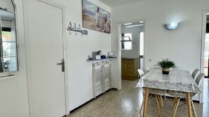 Een eetruimte met een tafel voor vier personen, een potplant en een schilderij aan de muur.