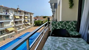 A balcony with a pool, a view of neighboring buildings, and a patterned sofa. - OMEGA 4 2-C (Estartit)