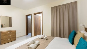 Een hotelkamer met een bed, een houten dressoir, een spiegel en een deur.