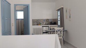 A compact kitchen with a dining area, a window, and a door leading to another room. - Apartment In A Hotel 'Pico Bello Patmos 22' with Mountain View, Wi-Fi and Air Conditioning (Patmos)