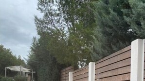 A narrow outdoor corridor with a gravel path, a wooden fence, and a concrete wall with a small garden area. - Superbe Maison 1min Plage (Sausset-les-Pins)