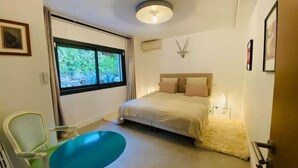 A bedroom with a bed, a window, a chair, and a table. - Superbe Maison 1min Plage (Sausset-les-Pins)