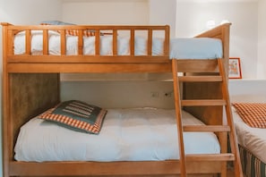 A bunk bed with a ladder, a pillow, and a bedside table.