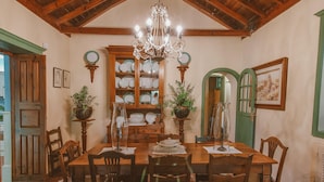 A dining room with a wooden table, chairs, a chandelier, and a green door. - Country House in Gran Canaria with Private Pool (San Mateo)