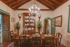 A dining room with a wooden table, chairs, a chandelier, a green door, and a wall-mounted plate rack. - Country House in Gran Canaria with Private Pool (San Mateo)
