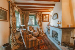 A traditional room with a fireplace, two armchairs, a patterned rug, and a window with curtains. - Country House in Gran Canaria with Private Pool (San Mateo)