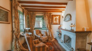 A cozy room with a fireplace, two armchairs, a patterned rug, and a green window. - Country House in Gran Canaria with Private Pool (San Mateo)