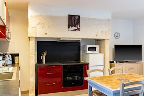 A compact kitchen with red cabinets, a microwave, and a dining area with a table and chairs.