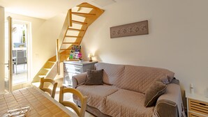 Ett modernt vardagsrum med en trappa, en beige soffa och ett litet bord med en lampa.