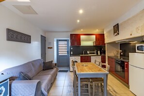 A compact living space with a kitchenette, a dining area, and a sofa.