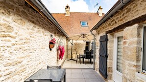 A stone building with a tiled patio, outdoor seating, and a chimney. - Holiday Home 'La Boutique Germain 4 to 6 Persons' with Private Terrace (Lacave)