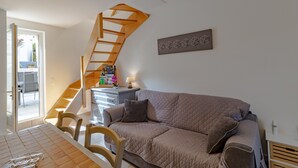 A living room with a sofa, a wooden staircase, a small table with a lamp, and a wall art piece. - Holiday Home 'La Boutique Germain 4 to 6 Persons' with Private Terrace (Lacave)