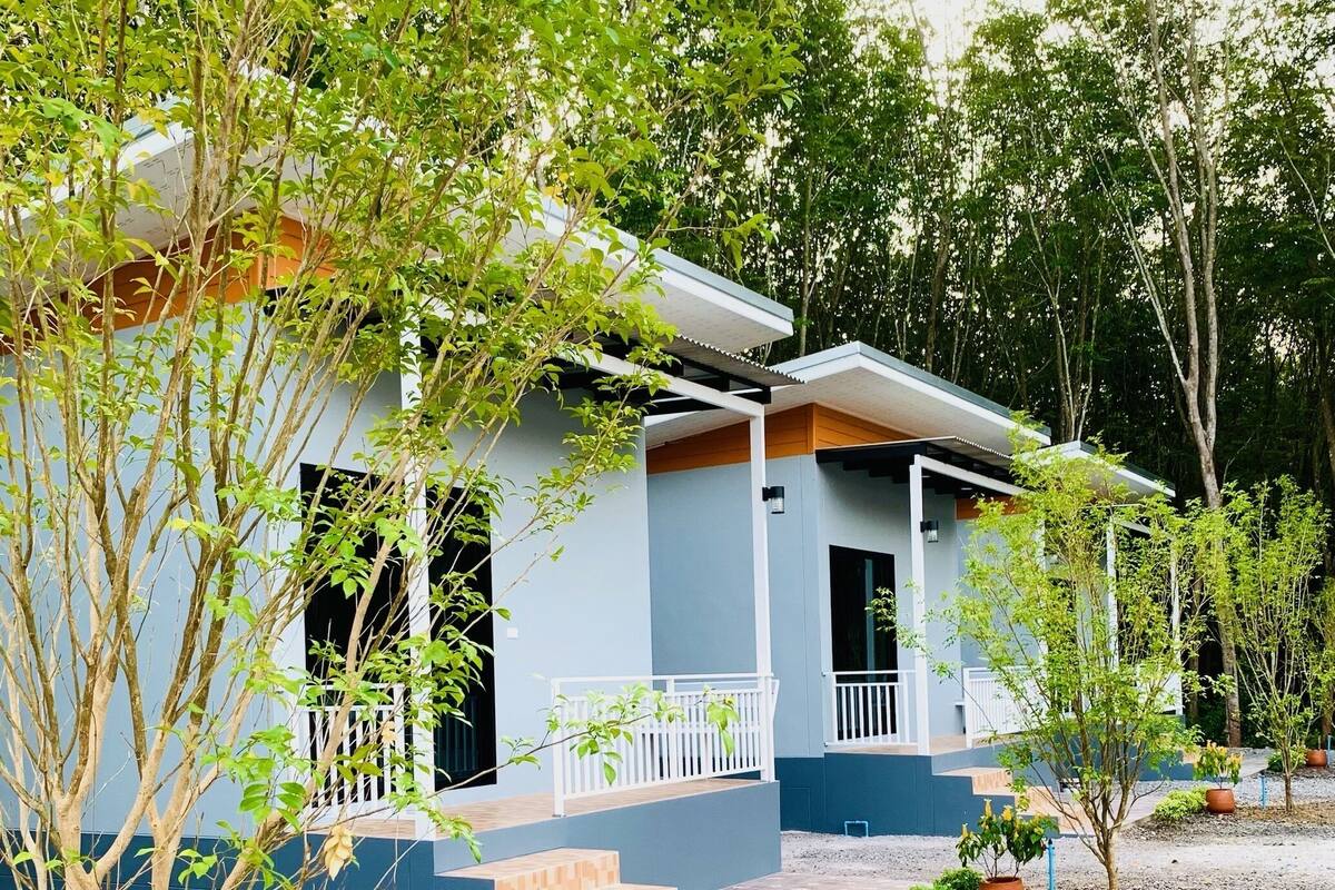Una moderna casa a due piani con facciata blu, ringhiere bianche e un piccolo portico.