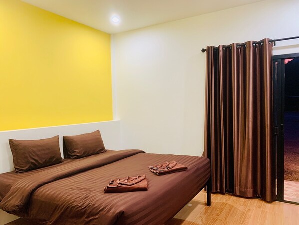 A room with a bed, a yellow wall, and a curtain.