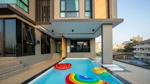 A rooftop swimming pool with inflatable toys and a modern building in the background. - Increase Hotel&residence (Bang Phli)