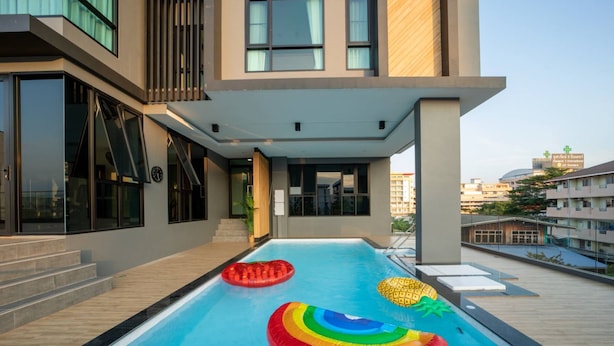A rooftop swimming pool with inflatable toys and a modern building in the background. - Increase Hotel&residence (Bang Phli)