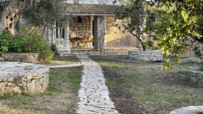 Une maison en pierre avec un chemin en pierre menant à un espace extérieur aménagé et abrité.