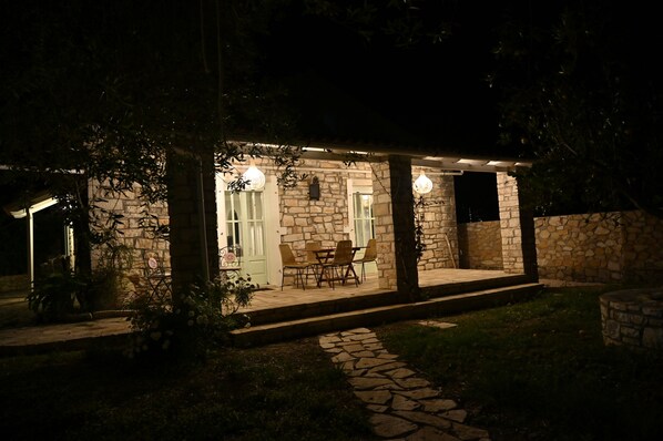 Un bâtiment en pierre doté d’un patio couvert, d’un espace extérieur aménagé pour s’asseoir et d’un chemin menant à l’entrée.