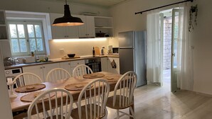Eine moderne Küche mit weißen Schränken, einem Holztisch mit gewobenen Unterlagen und einem eingebauten Backofen.