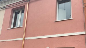 Ein pinkfarbenes Gebäude mit der Nummer 66, Fenstern und einer Tür.