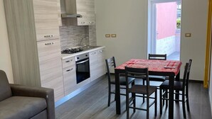 Eine moderne Küche mit Essbereich, einer Sitzecke und Blick durch eine geöffnete Tür.
