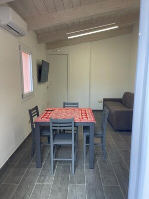 Un espace repas comprenant une table, des chaises et un téléviseur fixé au mur.