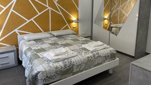Ein modernes Schlafzimmer mit Wandverkleidung im geometrischen Muster, einem großen Bett mit Steppdecke, Nachttischlampen und einem Spiegel.