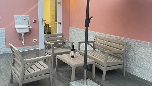 Ein Sitzbereich im Freien mit Tisch, Stühlen und einem großen Sonnenschirm.