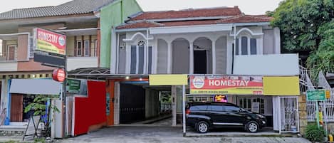 A two-story building with a red roof and a sign for Homestay.
