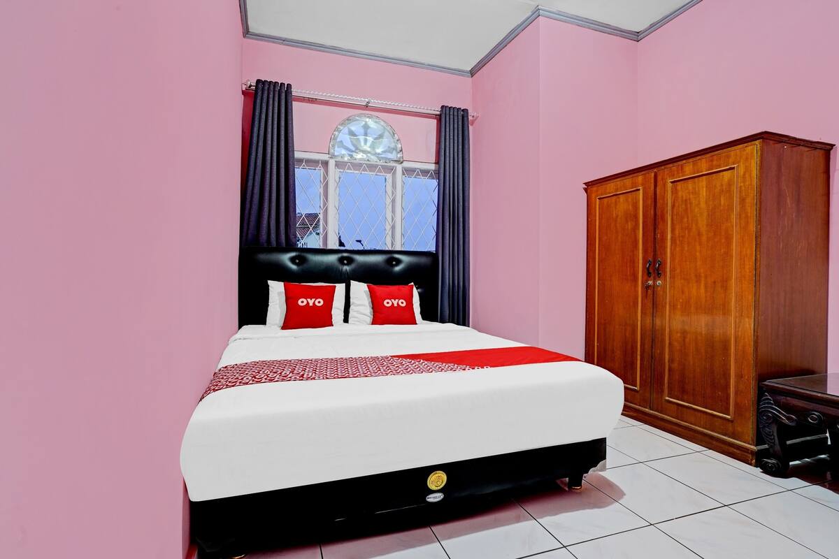 Une chambre à coucher avec un lit, une armoire et une fenêtre avec des rideaux.