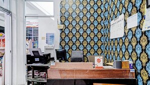 Un comptoir d’accueil avec un papier peint à motifs, un ordinateur et un banc en bois.