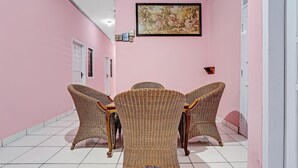 Une pièce aux murs roses, une table à manger avec des chaises en osier et un tableau encadré accroché au mur.