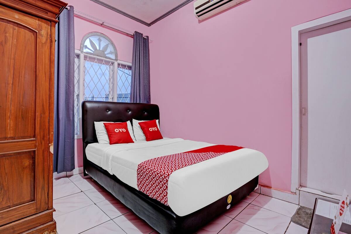Une chambre à coucher avec un lit, des rideaux, une fenêtre et une armoire.