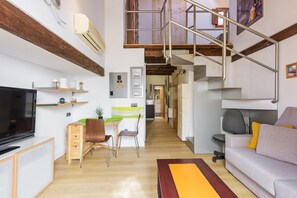 Ein moderner Wohnraum mit Flachbildfernseher, Essbereich, Sofa und Treppe.