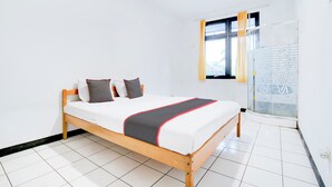 Une chambre à coucher avec un lit en bois, des murs blancs et une fenêtre avec des rideaux.