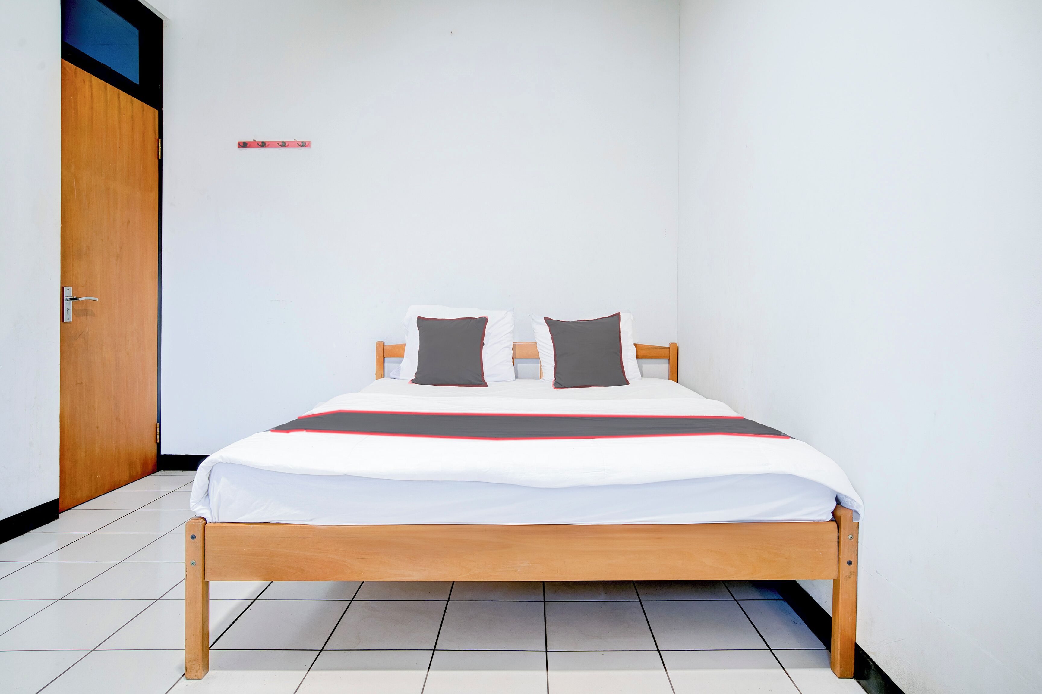 A single bed with a wooden frame, white bedding, and two pillows.