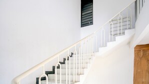 Un escalier avec des rampes et des marches blanches, menant à un palier doté d’une porte en bois.