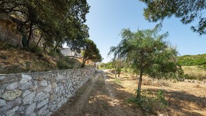 A stone wall, a dirt path, and trees. - Holiday Home 'Cala Lunga' with Private Terrace and Private Garden (Carloforte)