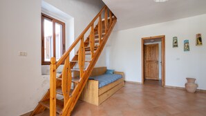 A room with a wooden staircase, a bed, a door, and a window. - Holiday Home 'Cala Lunga' with Private Terrace and Private Garden (Carloforte)