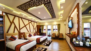 A hotel room with two beds, a wooden wardrobe, a desk with a computer, and a TV mounted on the wall. - MeroStay 172 Hotel JP (Kathmandu)