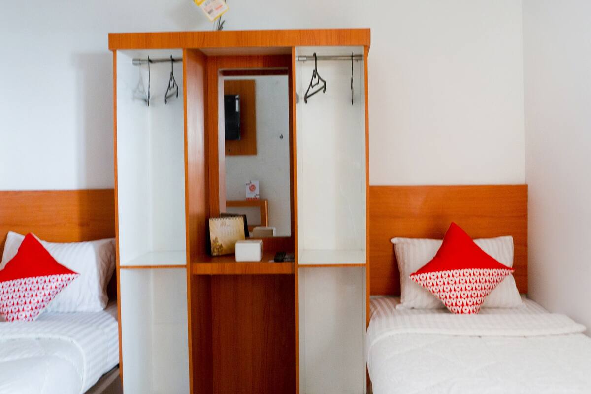 Hotellihuone, jossa on kaksi sänkyä, puinen vaatekaappi ja peili.