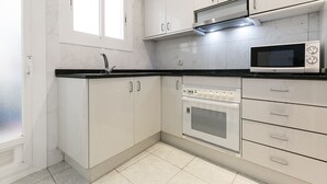 Una cocina moderna con armarios blancos, encimera negra, microondas integrado y horno.