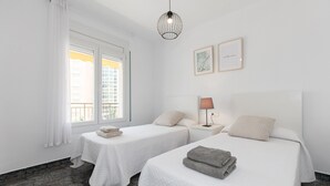 Habitación de hotel con dos camas, una ventana con cortinas, una lámpara y una obra de arte en la pared.