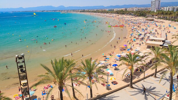 Una playa con muchos sombrillas y gente.