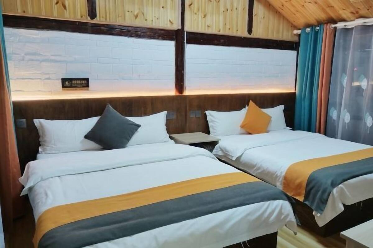 Ein Hotelzimmer mit zwei Betten, Holzbalkendecke, Backsteinwand und einem Schild über den Betten.