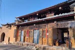 A traditional building with a tiled roof, wooden doors, and a small outdoor seating area.