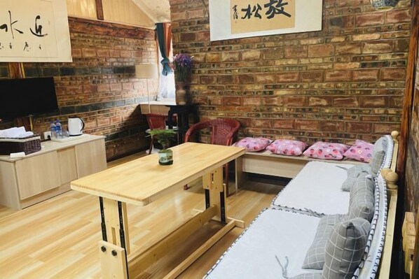 Une pièce chaleureuse avec une table en bois, un canapé agrémenté de coussins à motifs et un mur en briques.