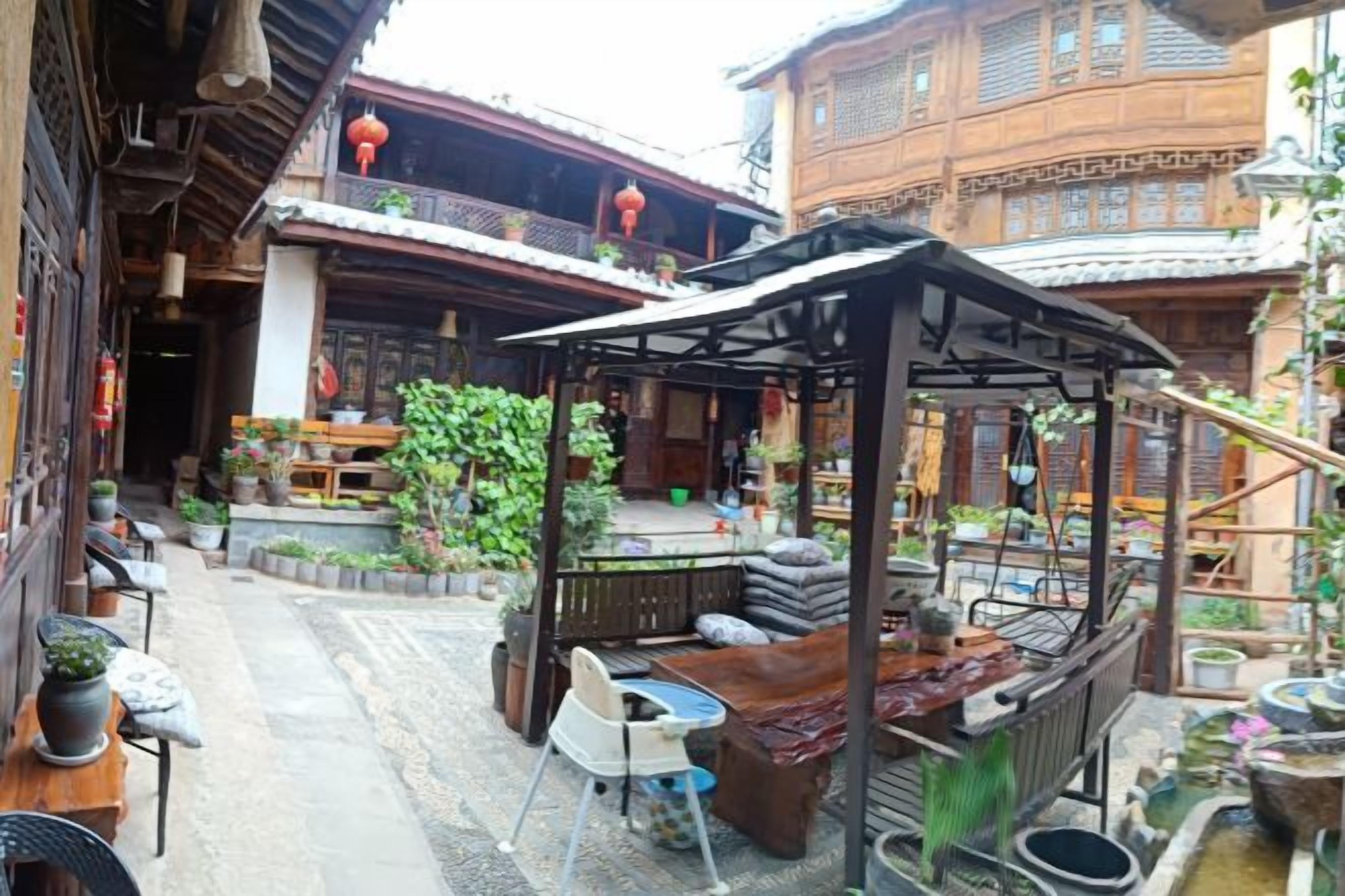 A courtyard with traditional wooden architecture, outdoor seating, and a small covered area.