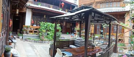 A courtyard with traditional wooden architecture, outdoor seating, and a small covered area.