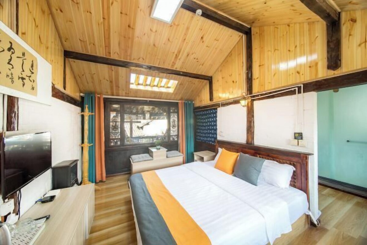 Un intérieur en bois comprenant un lit, une télévision et un bureau.